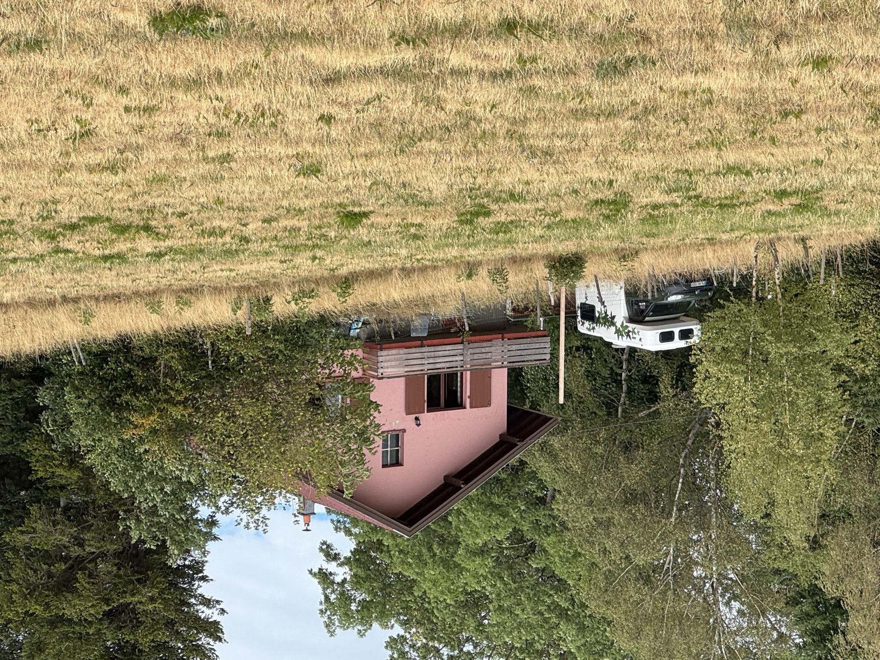 Unser Haus in den Vogesen — Chalet mit Holzbalkon, umgeben von Wiese und Bäumen